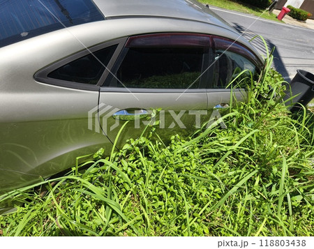 A silver car that has a broken tire and is covered with leaves A silver car that has a broken tire and is covered with leaves 118803438