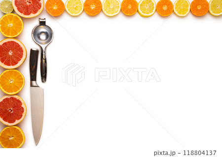 Fresh sliced and halved citrus fruits, a lemon squeezer and a kitchen knife on a white background. 118804137