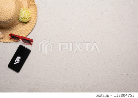 Summer, beach and vacation concept with free text space. Top view. Flat layout with women straw, sun glasses hat and a smartphone with wireless earphones on a fine sandy background Summer, beach and vacation concept with free text space. Top view. Flat layout with women straw, sun glasses hat and a smartphone with wireless earphones on a fine sandy background 118804753