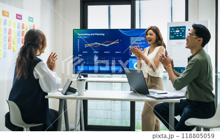 group of investor celebrating a successful outcome in a modern office high-fiving each other in front of a digital screen displaying financial data 118805059