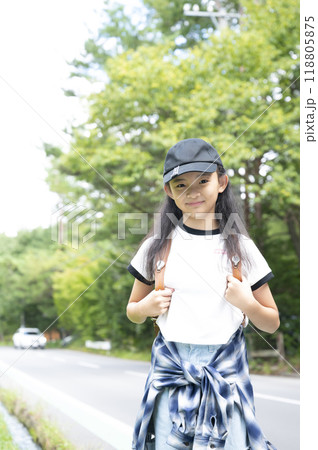田舎の通学路の森の中を歩く、ランドセルを背負った、下校中の小学生の女の子 118805875