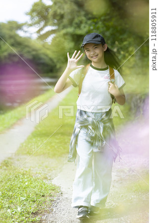 田舎の通学路の森の中を歩く、ランドセルを背負った、下校中の小学生の女の子 田舎の通学路の森の中を歩く、ランドセルを背負った、下校中の小学生の女の子 118805911