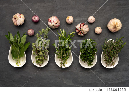 Fresh herbs in procelain dishes and fresh garlic on a large slate plate Fresh herbs in procelain dishes and fresh garlic on a large slate plate 118805936