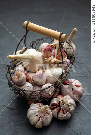 Garlic bulbs and cloves in a small old metal basket on a black slate plate Garlic bulbs and cloves in a small old metal basket on a black slate plate 118805948