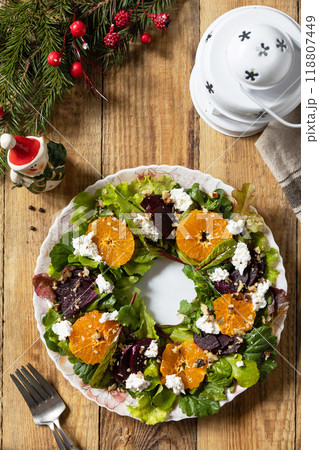 Christmas appetizer New year meal idea. Christmas wreath salad with beetroot, tangerines, feta cheese and pecans on the rustic table. Christmas appetizer New year meal idea. Christmas wreath salad with beetroot, tangerines, feta cheese and pecans on the rustic table. 118807449