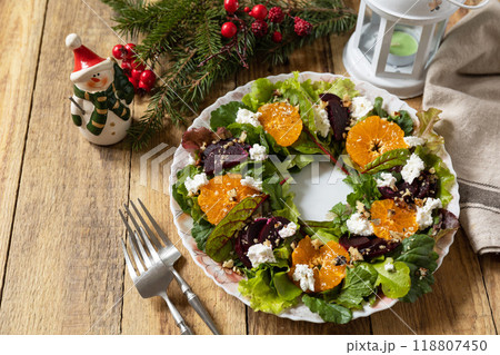 Christmas appetizer New year meal idea. Christmas wreath salad with beetroot, tangerines, feta cheese and pecans on the rustic table. 118807450