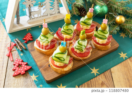 Creative appetizers christmas. Canapes Christmas tree of salami, cheese, olives, tomatoes and cucumbers with baguette on a rustic table. 118807480