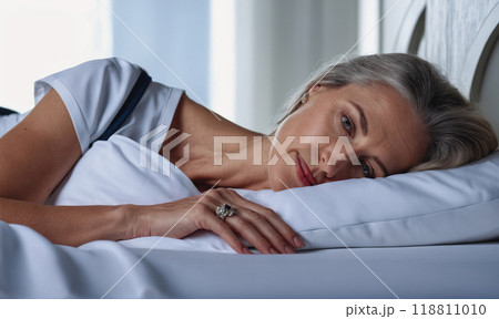 A woman is laying on a bed with her hand on her face 118811010