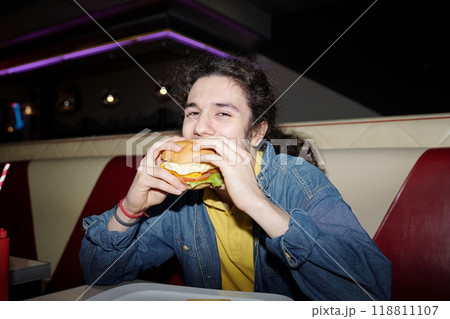 Eating Burger in Casual Diner Setting with Joyful Expression Eating Burger in Casual Diner Setting with Joyful Expression 118811107