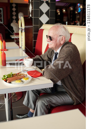 Senior Man Enjoying Breakfast in Retro Diner Senior Man Enjoying Breakfast in Retro Diner 118811178