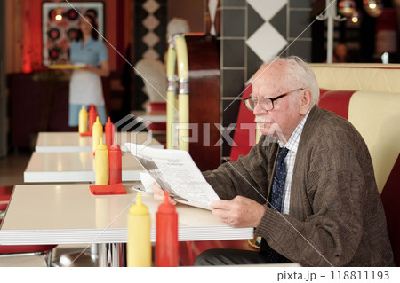 Elderly Man Reading Menu in Retro Style Diner Booth Elderly Man Reading Menu in Retro Style Diner Booth 118811193