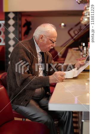 Elderly Man Reading Document at Restaurant Counter 118811229