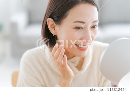 鏡を見てスキンケアをする女性 118812424