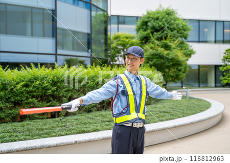 誘導棒を持って交通誘導をするガードマン男性 118812963
