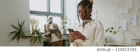 Website banner of African American businesswoman checking social media while her coworker using tablet in background Website banner of African American businesswoman checking social media while her coworker using tablet in background 118813193