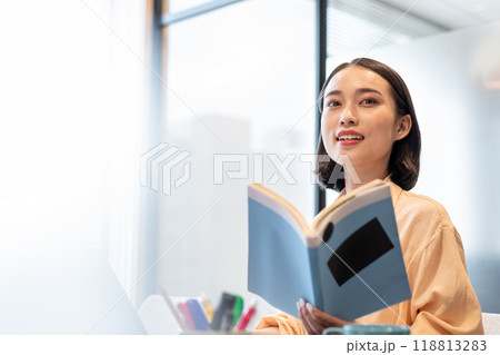 参考書を片手に笑みを浮かべてコチラを見る女性 118813283