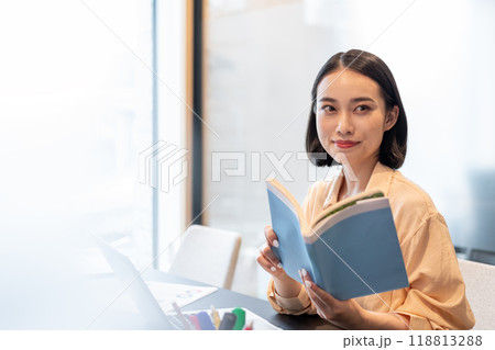 本を片手に微笑みを浮かべる女性 118813288