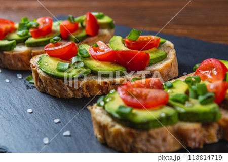 Avocado toast topped with tomato and green onion on a slice of carrot bread 118814719