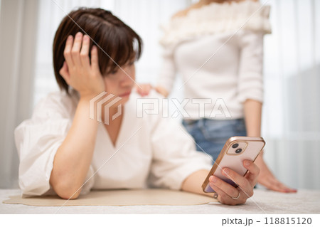 スマートフォンを見る女性の手元と傍に立つ女性 118815120