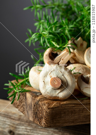 White champignons with rosemary on a wooden board. White champignons with rosemary on a wooden board. 118815987