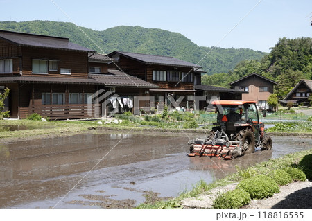 山間の水田をトラクターで耕している農夫 山間の水田をトラクターで耕している農夫 118816535