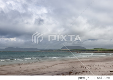 A tranquil view of Strandhill beach with gentle waves, distant hills along the coastline A tranquil view of Strandhill beach with gentle waves, distant hills along the coastline 118819066