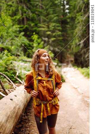 Traveler with yellow backpack walks along hiking path among mountains in the forest. Enjoys nature. Traveler with yellow backpack walks along hiking path among mountains in the forest. Enjoys nature. 118819841