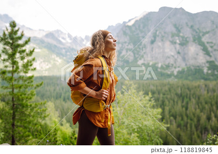 Happy woman with a yellow hiking backpack enjoying the mountain landscape. Travel concept. Happy woman with a yellow hiking backpack enjoying the mountain landscape. Travel concept. 118819845