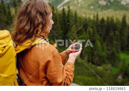 Wanderlust concept. Stylish woman holding a compass in her hand while traveling in the mountains. Wanderlust concept. Stylish woman holding a compass in her hand while traveling in the mountains. 118819861