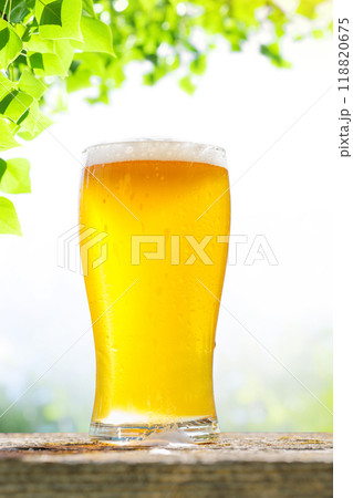 A glass of cold beer placed on a table with a soft outdoor bokeh background 118820675