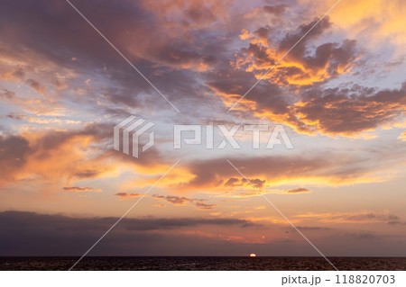 A dramatic and moody sunset sky filled with dark, swirling clouds 118820703
