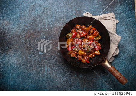 Sweet and sour pork in wok pan with peppers and pineapple top view, traditional Chinese dish, space for text 118820949