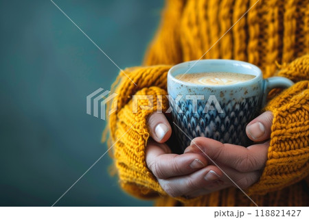 Hands in a warm knitted sweater holding a cup cozy autumn scene 118821427