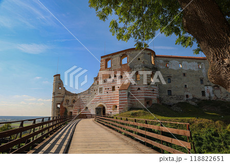 Wooden walkway leading to medieval castle ruins with striped walls, surrounded by scenic landscape, Poland Wooden walkway leading to medieval castle ruins with striped walls, surrounded by scenic landscape, Poland 118822651