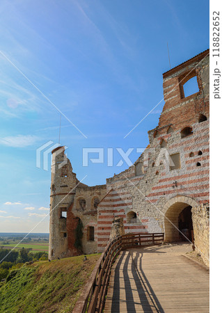 Ancient castle ruins with striped stone walls and wooden walkway under a clear blue sky in Poland Ancient castle ruins with striped stone walls and wooden walkway under a clear blue sky in Poland 118822652