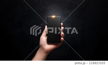 A person holding a smartphone with a glowing light at night 118823103