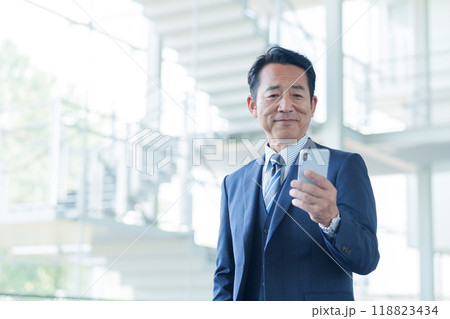 空港でスマートフォンを使う中高年のビジネスマン 空港でスマートフォンを使う中高年のビジネスマン 118823434