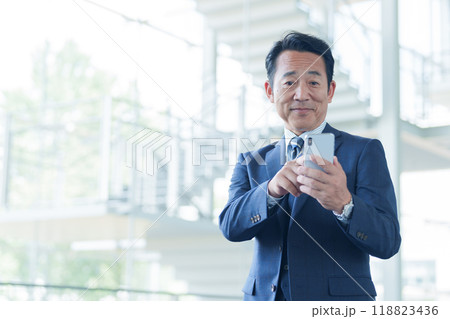 空港でスマートフォンを使う中高年のビジネスマン 空港でスマートフォンを使う中高年のビジネスマン 118823436