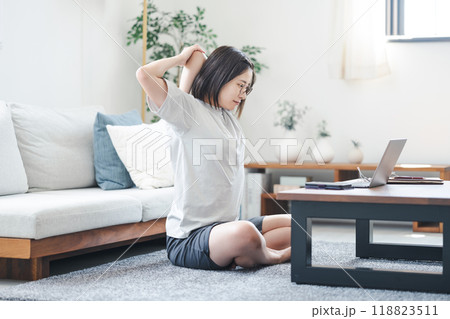 自宅のリビングでパソコンを見ながらストレッチをする女性 118823511