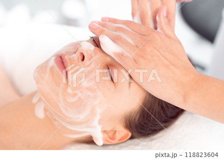 Therapist massaging woman's face with cream at Therapist massaging woman's face with cream at 118823604
