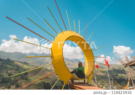 A woman sits in the middle of a yellow circle, traveling through the peruvian andes. Canta, Lima, Peru. 118823916