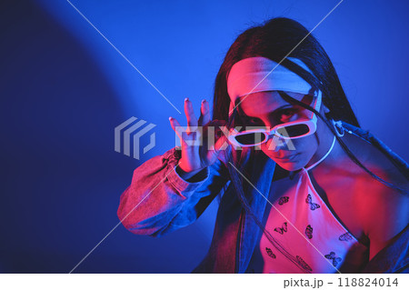 A woman wearing sunglasses and a bandana is posing for a photo. Urban dancer concept 118824014