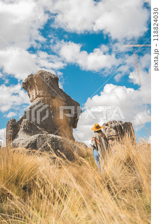 A woman wearing a yellow hat is walking through a field of Huayllay Stone Forest, Peru. 118824030