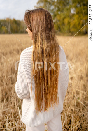 A Beautiful Woman with Long Flowing Hair Standing Gracefully in a Golden Wheat Field A Beautiful Woman with Long Flowing Hair Standing Gracefully in a Golden Wheat Field 118824277