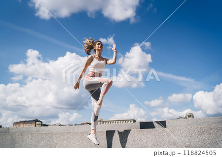 Energetic woman jogging up steps under blue sky, vitality and motion in an urban setting, concept of healthy city living 118824505
