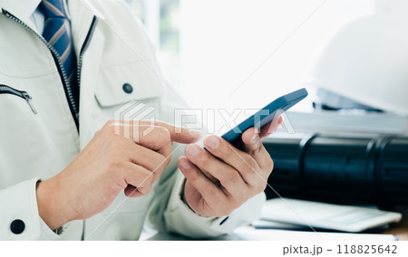 スマホを操作する作業服の男性の手元 スマホを操作する作業服の男性の手元 118825642