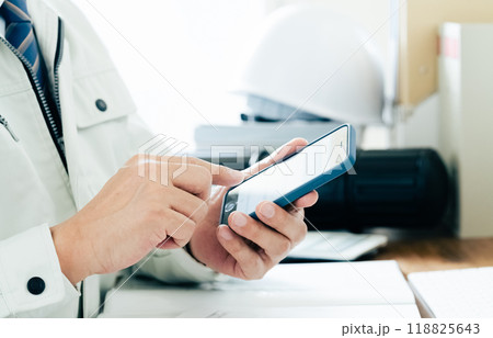 スマホを操作する作業服の男性の手元 118825643