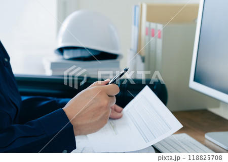 書類をチェックする作業服の男性 118825708