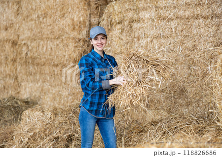 Young female farmer standing in hayloft with hay in hands Young female farmer standing in hayloft with hay in hands 118826686