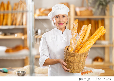 Senior female baker worker shows baguette 118826985